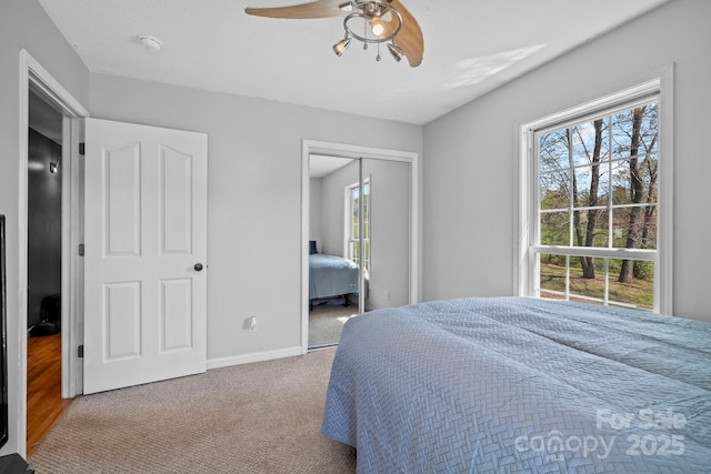 carpeted bedroom with a closet, baseboards, and a ceiling fan