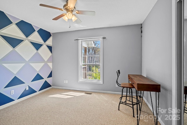 interior space featuring carpet flooring, baseboards, a ceiling fan, and visible vents