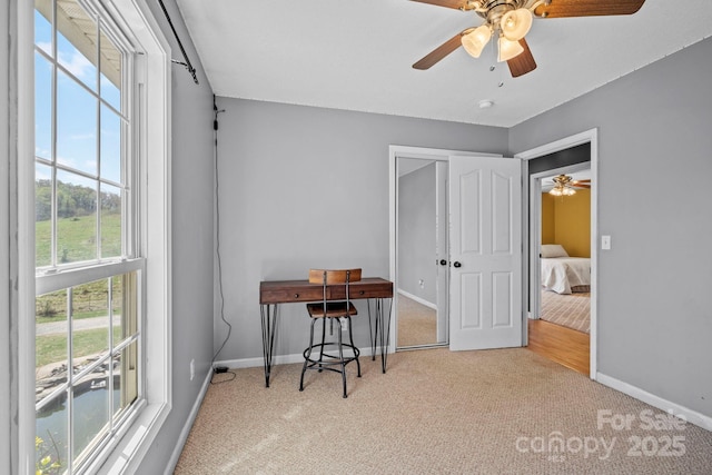 office area with carpet flooring, baseboards, and a ceiling fan