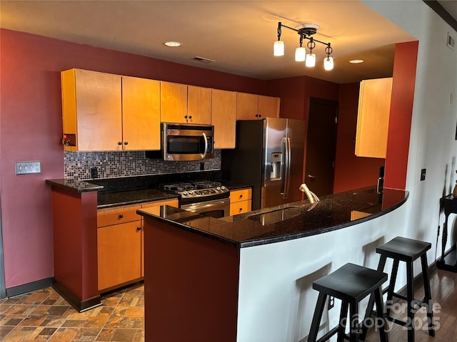 kitchen featuring a sink, tasteful backsplash, baseboards, visible vents, and appliances with stainless steel finishes