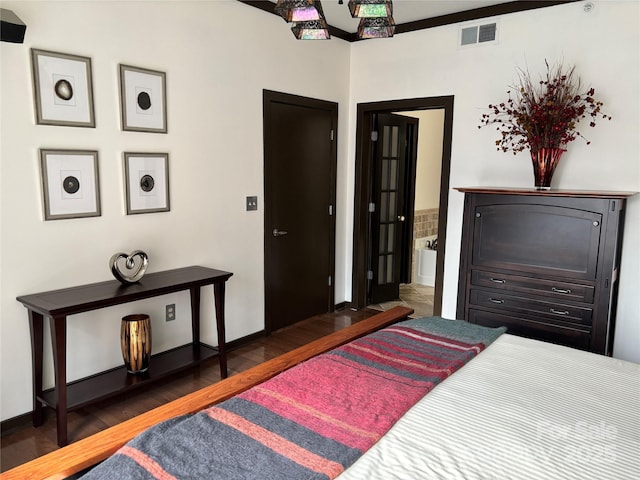 bedroom featuring wood finished floors, visible vents, baseboards, and ensuite bathroom