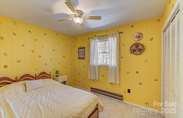 bedroom with light colored carpet, a closet, a baseboard heating unit, and ceiling fan