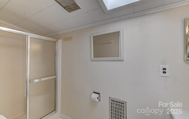 bathroom featuring a shower with door and visible vents