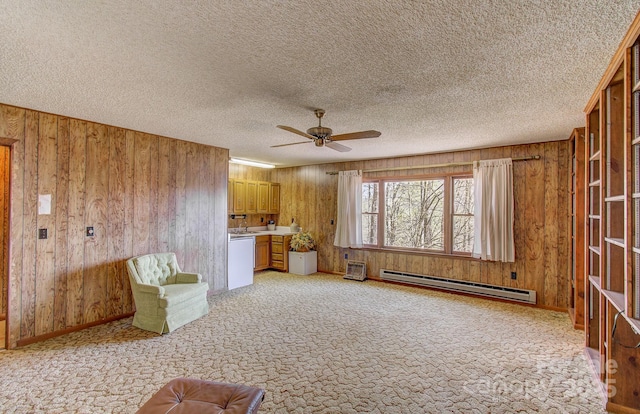 unfurnished living room featuring wooden walls, ceiling fan, a baseboard heating unit, and light carpet