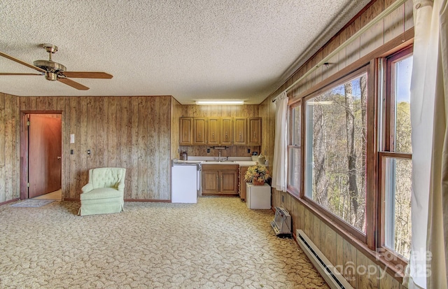 kitchen with brown cabinets, light countertops, dishwashing machine, and a wealth of natural light