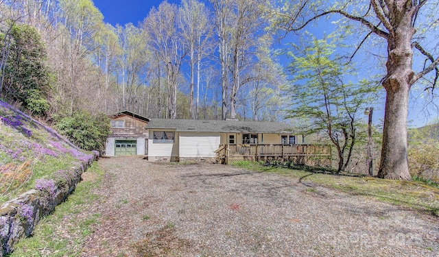 ranch-style home with a garage, a deck, and driveway