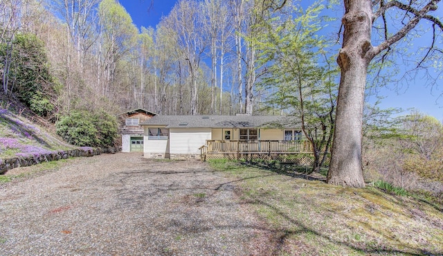 ranch-style home with a deck and dirt driveway