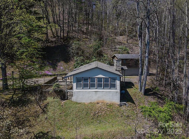 view of property exterior featuring a wooded view and a deck