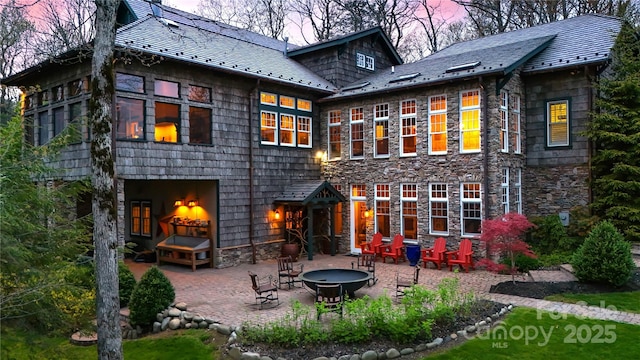 205 W Indrio Rd, Blowing Rock, NC 28605 - back of property at dusk with an outdoor fire pit, a patio, and stone siding