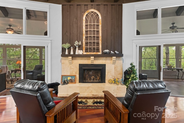 living area with a ceiling fan, wood finished floors, and a tile fireplace