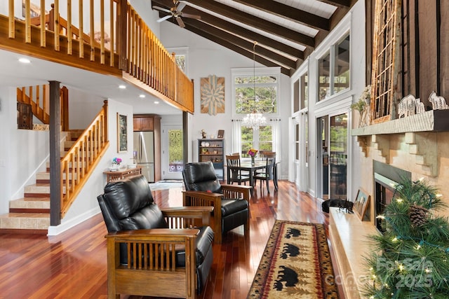 living room featuring beamed ceiling, hardwood / wood-style flooring, an inviting chandelier, and stairway