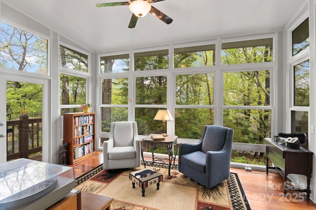 sunroom / solarium with wood finished floors, a healthy amount of sunlight, and a wall of windows
