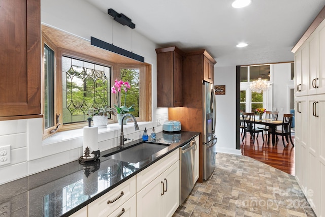 kitchen featuring plenty of natural light, a sink, appliances with stainless steel finishes, and a chandelier