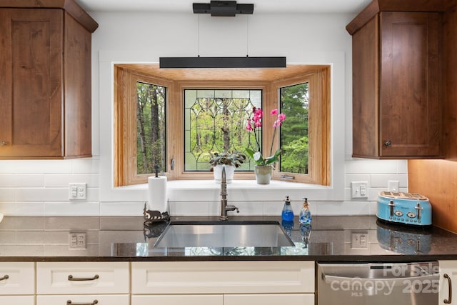 kitchen featuring a sink, dark stone counters, backsplash, and dishwasher
