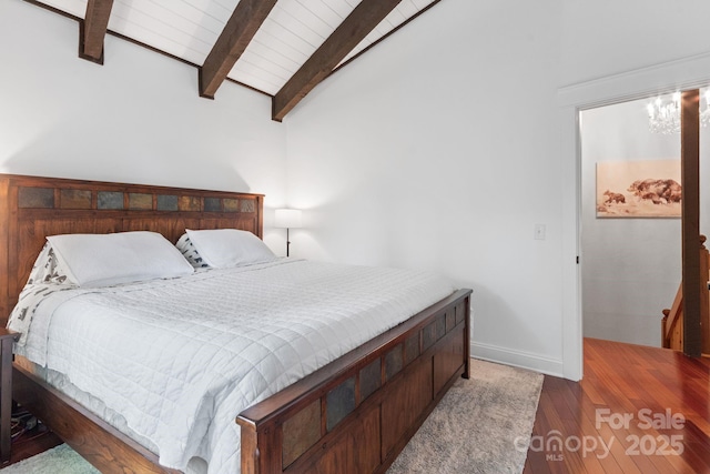 bedroom with vaulted ceiling with beams, baseboards, and wood finished floors