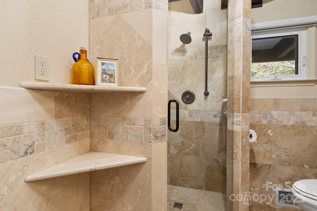 bathroom featuring tile walls, a shower stall, toilet, and visible vents