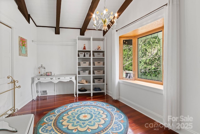 interior space featuring baseboards, beamed ceiling, wood finished floors, and a chandelier
