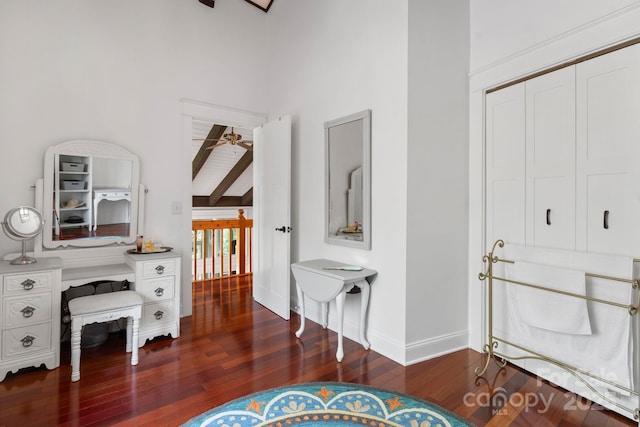interior space featuring ceiling fan, a towering ceiling, wood finished floors, baseboards, and beamed ceiling