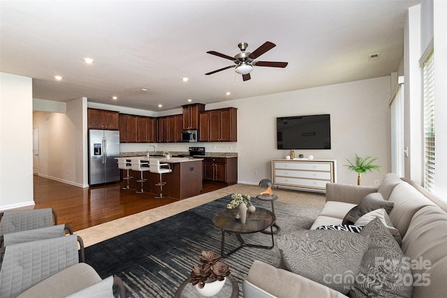 living area featuring visible vents, baseboards, recessed lighting, a ceiling fan, and dark wood finished floors