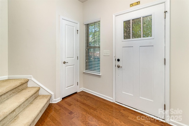 entrance foyer with dark wood-type flooring, baseboards, and stairway