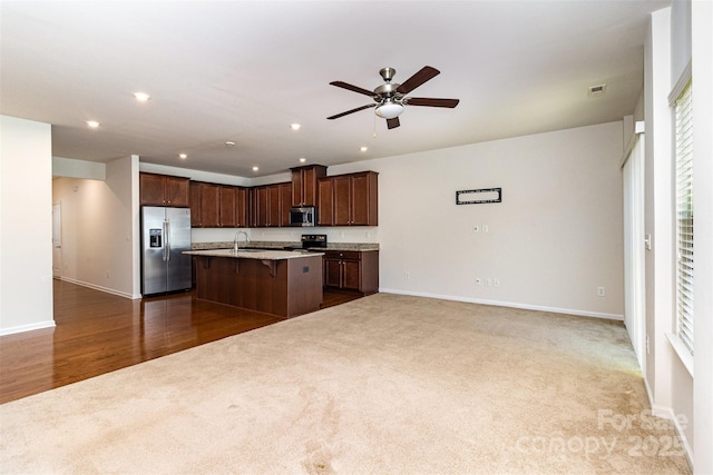 kitchen featuring appliances with stainless steel finishes, ceiling fan, a kitchen bar, and dark carpet