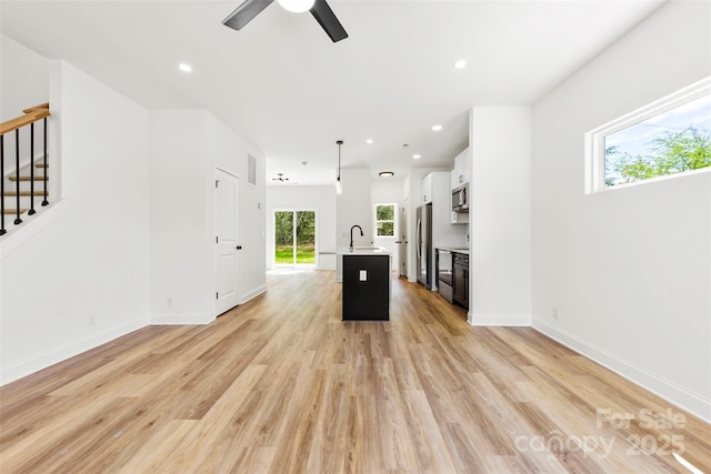 2043 Greenoak Dr, Shelby, NC 28152 - unfurnished living room featuring visible vents, a sink, ceiling fan, light wood finished floors, and stairs