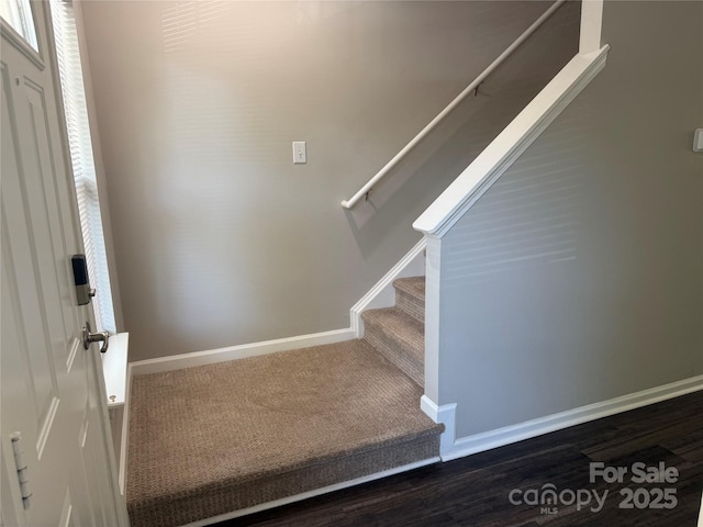 staircase featuring baseboards and carpet