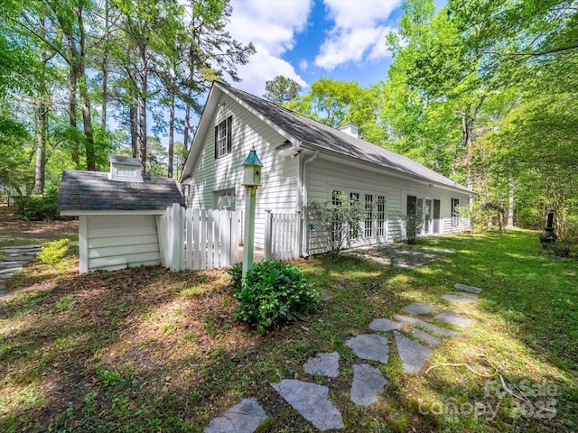 view of side of property with a yard, french doors, and a chimney