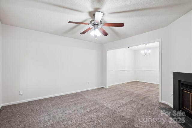 unfurnished living room featuring a fireplace with flush hearth, carpet floors, baseboards, and ceiling fan with notable chandelier