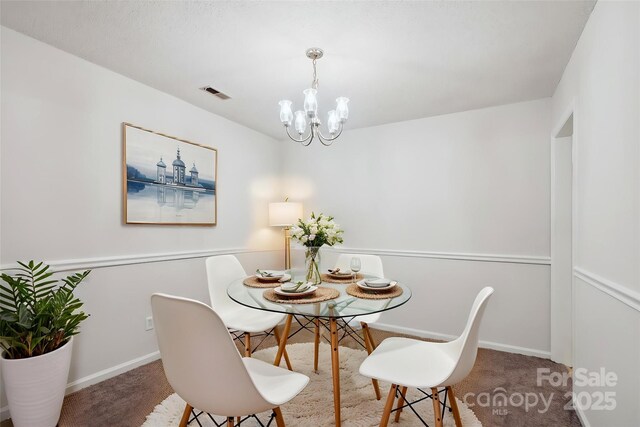 carpeted dining room featuring baseboards, visible vents, and an inviting chandelier