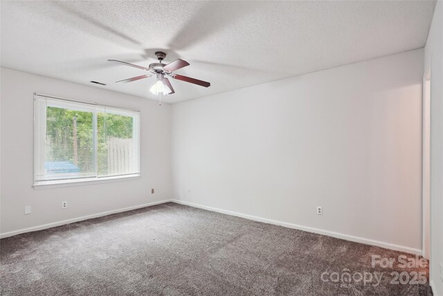 carpeted empty room with baseboards, a textured ceiling, ceiling fan, and visible vents