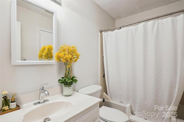 bathroom featuring vanity, shower / tub combo with curtain, and toilet