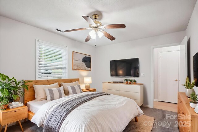 bedroom with visible vents, a ceiling fan, baseboards, and light colored carpet