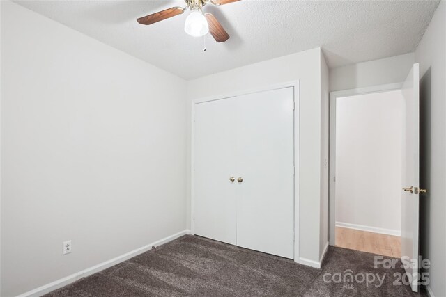 unfurnished bedroom featuring a closet, baseboards, a ceiling fan, and dark colored carpet