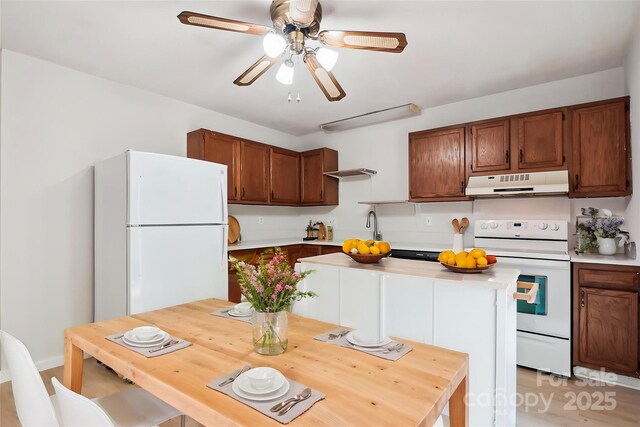 kitchen with a ceiling fan, light countertops, a sink, under cabinet range hood, and white appliances