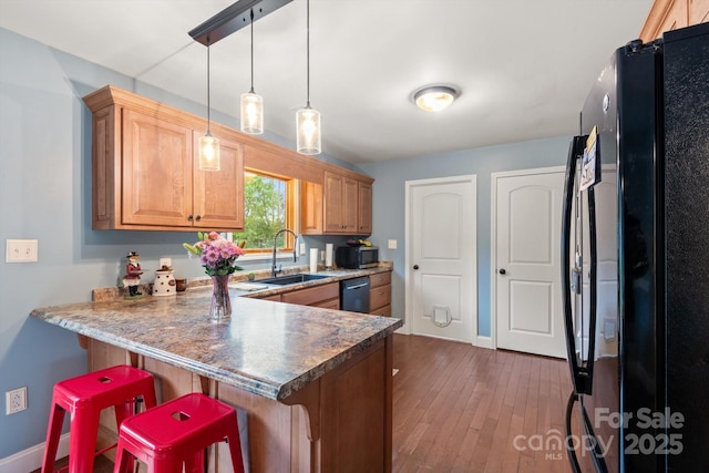 1091 Bill Collins Rd, Columbus, NC 28722 - kitchen with black appliances, a sink, a peninsula, a breakfast bar area, and dark wood-type flooring
