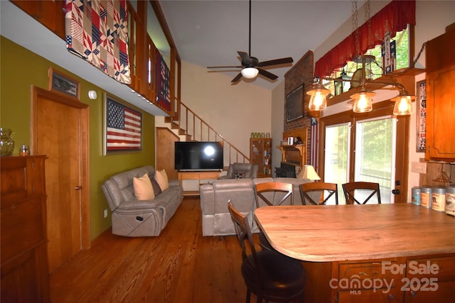 dining room featuring a ceiling fan, a towering ceiling, wood finished floors, and stairway