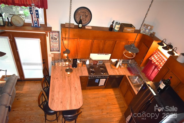 kitchen with brown cabinets, under cabinet range hood, light wood-type flooring, and oven
