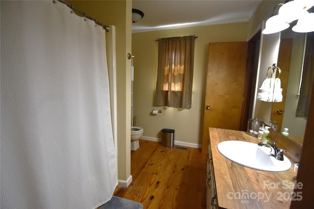bathroom featuring crown molding, wood finished floors, baseboards, vanity, and toilet
