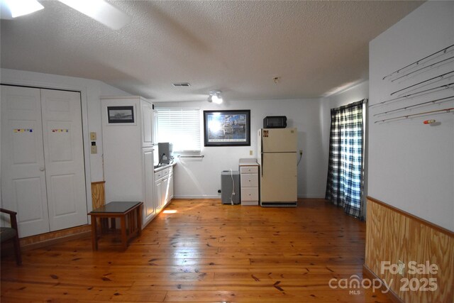 interior space featuring visible vents, a textured ceiling, and light wood-type flooring