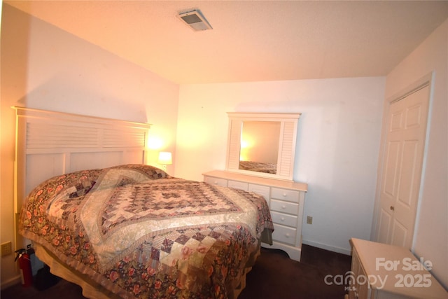 bedroom with baseboards, dark colored carpet, and visible vents