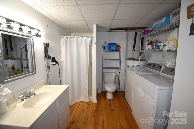 full bathroom featuring a paneled ceiling, washing machine and clothes dryer, wood finished floors, vanity, and toilet