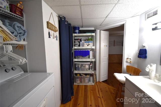 clothes washing area with washer / clothes dryer, laundry area, visible vents, and wood finished floors