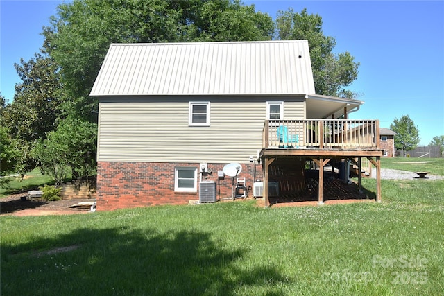back of property with a lawn, central AC, a deck, and metal roof