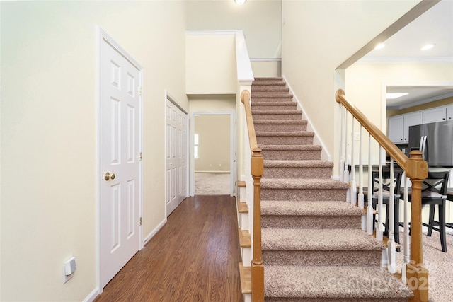 stairs with baseboards, crown molding, wood finished floors, and recessed lighting
