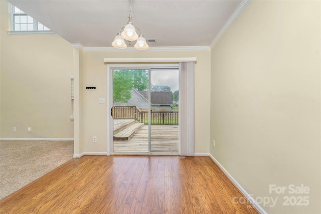 spare room with wood finished floors, a wealth of natural light, baseboards, and ornamental molding