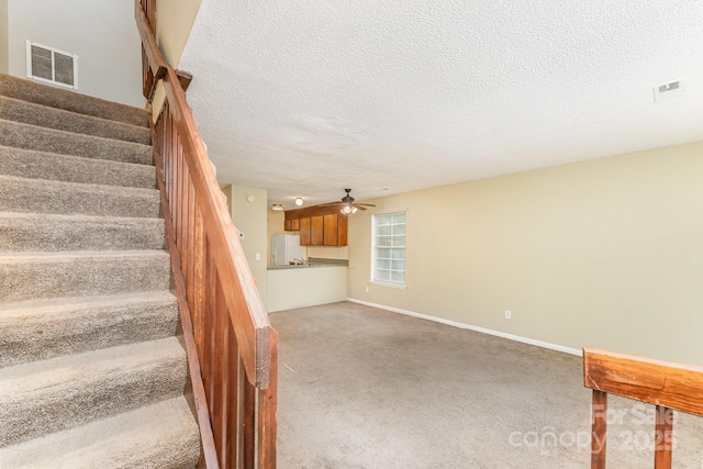 stairs with visible vents, baseboards, a ceiling fan, carpet, and a textured ceiling
