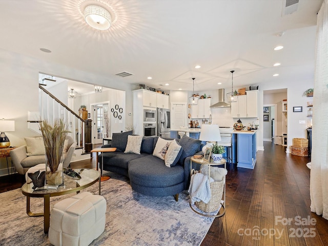 living room featuring dark wood-style floors, visible vents, and stairway
