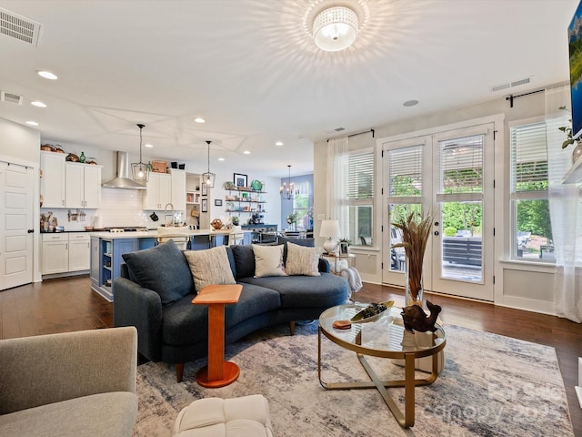 living area with dark wood-type flooring, visible vents, and a notable chandelier