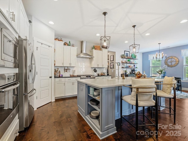 kitchen featuring recessed lighting, stainless steel appliances, a sink, dark wood-style floors, and wall chimney exhaust hood